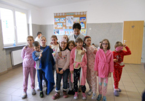 Dzień piżamowy - uczniowie klasy 2 w piżamkach na korytarzu szkolnym z panią wicedyrektor.