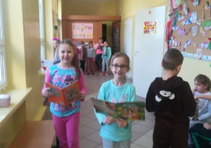 Dzieci podczas przerwy na korytarzu oglądają książeczki.