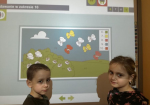Dziewczynka i chłopiec przy tablicy interaktywnej.
