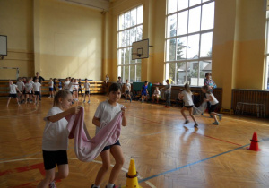 Uczniowie klas 1 SP12 oraz klas 3 SP7 bawią się na torze przeszkód na dużej sali gimnastycznej